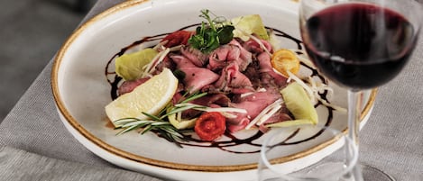 A plate of food with a glass of red wine on a table.