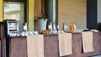 A breakfast buffet setup with coffee makers, croissants, and juice dispensers.