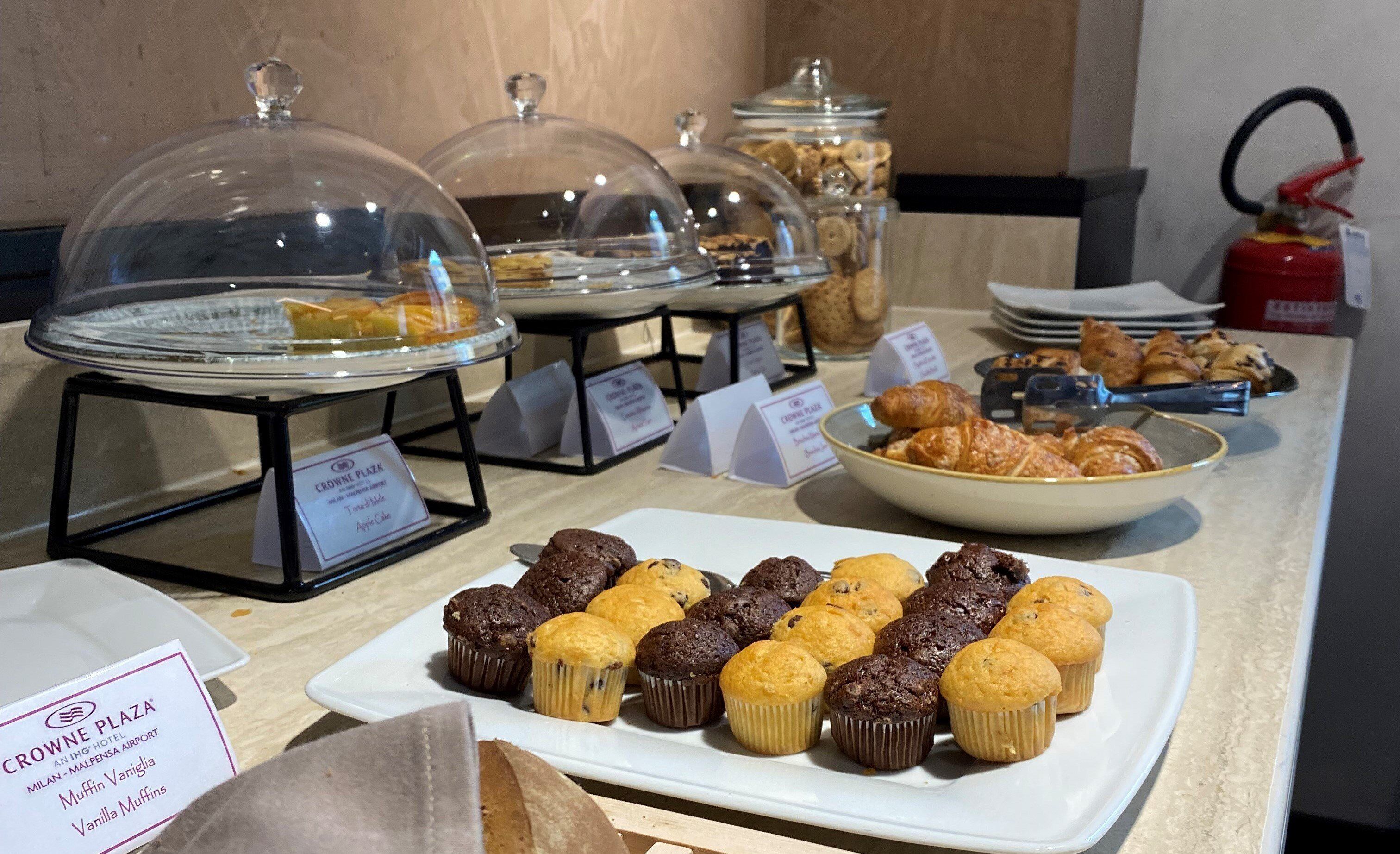 A breakfast buffet with various muffins and pastries displayed on a counter.