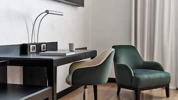Habitación de hotel moderna con escritorio, dos sillas, televisor de pantalla plana y un libro.