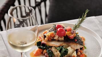 A plate of food with a glass of white wine on a table.
