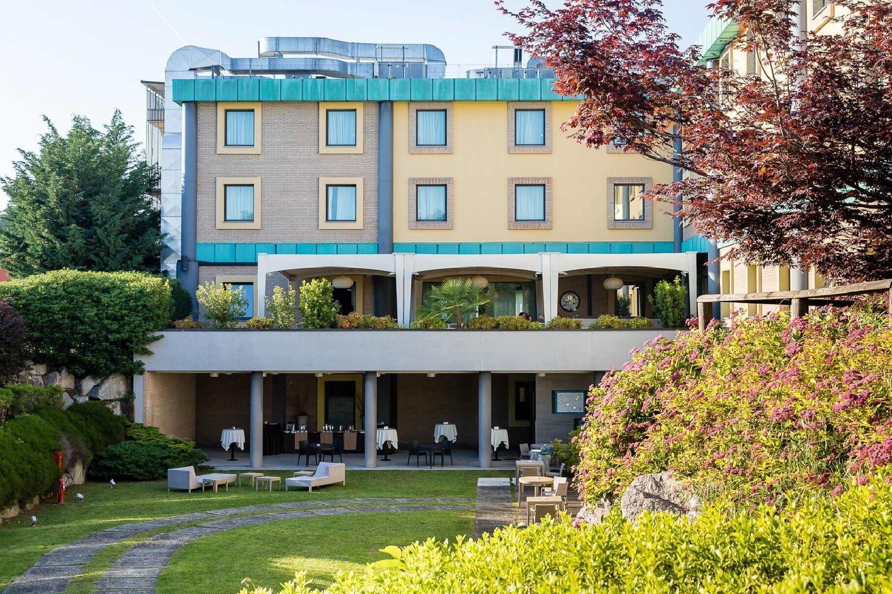 Un hôtel au design moderne, avec une structure à deux étages, un toit plat et un espace extérieur aménagé avec des sièges.