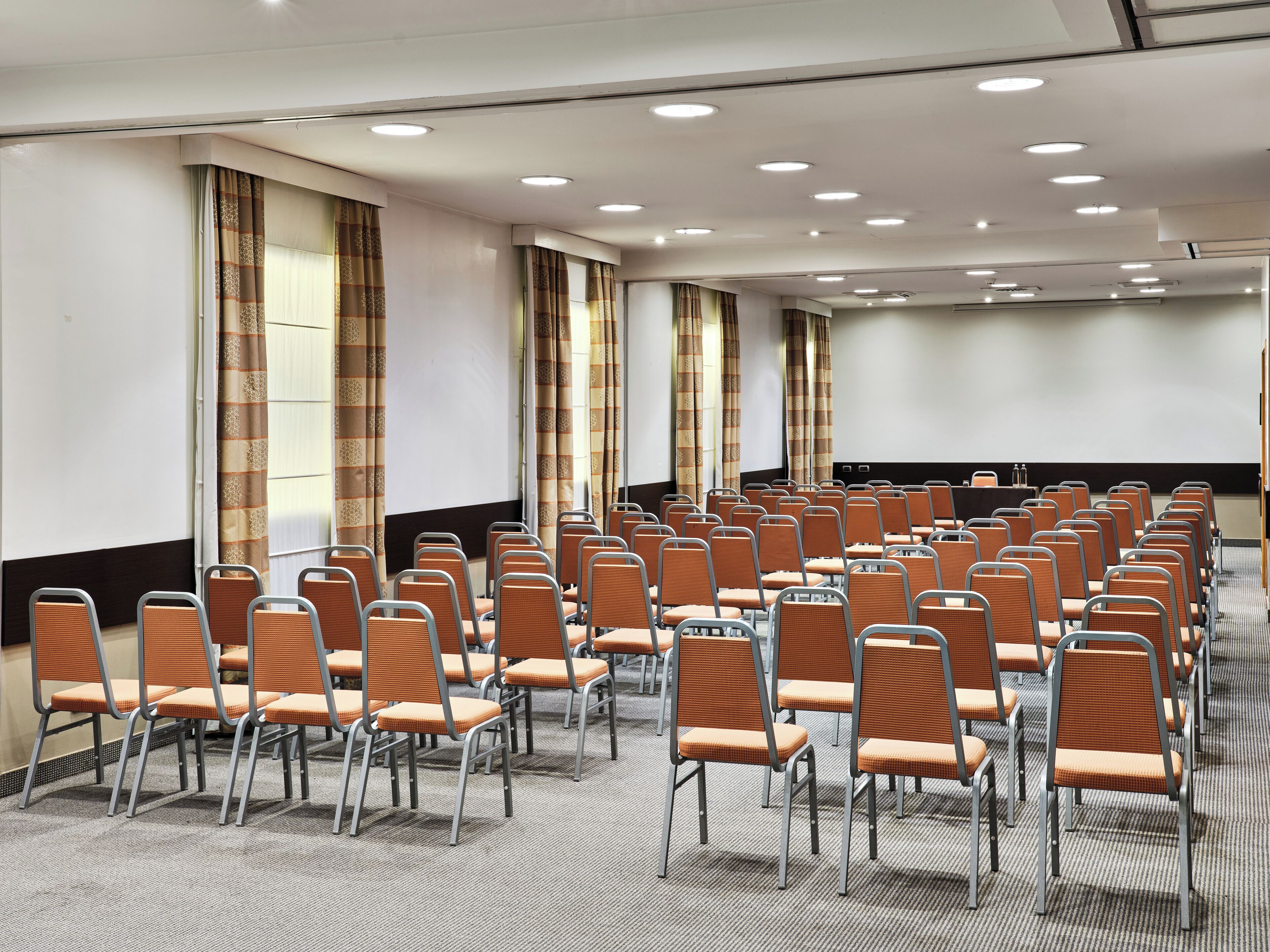 A conference room with rows of chairs, a projector screen, and a podium.