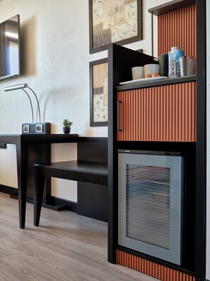 A modern office space with a black desk, a mounted computer, and a wall-mounted radiator.