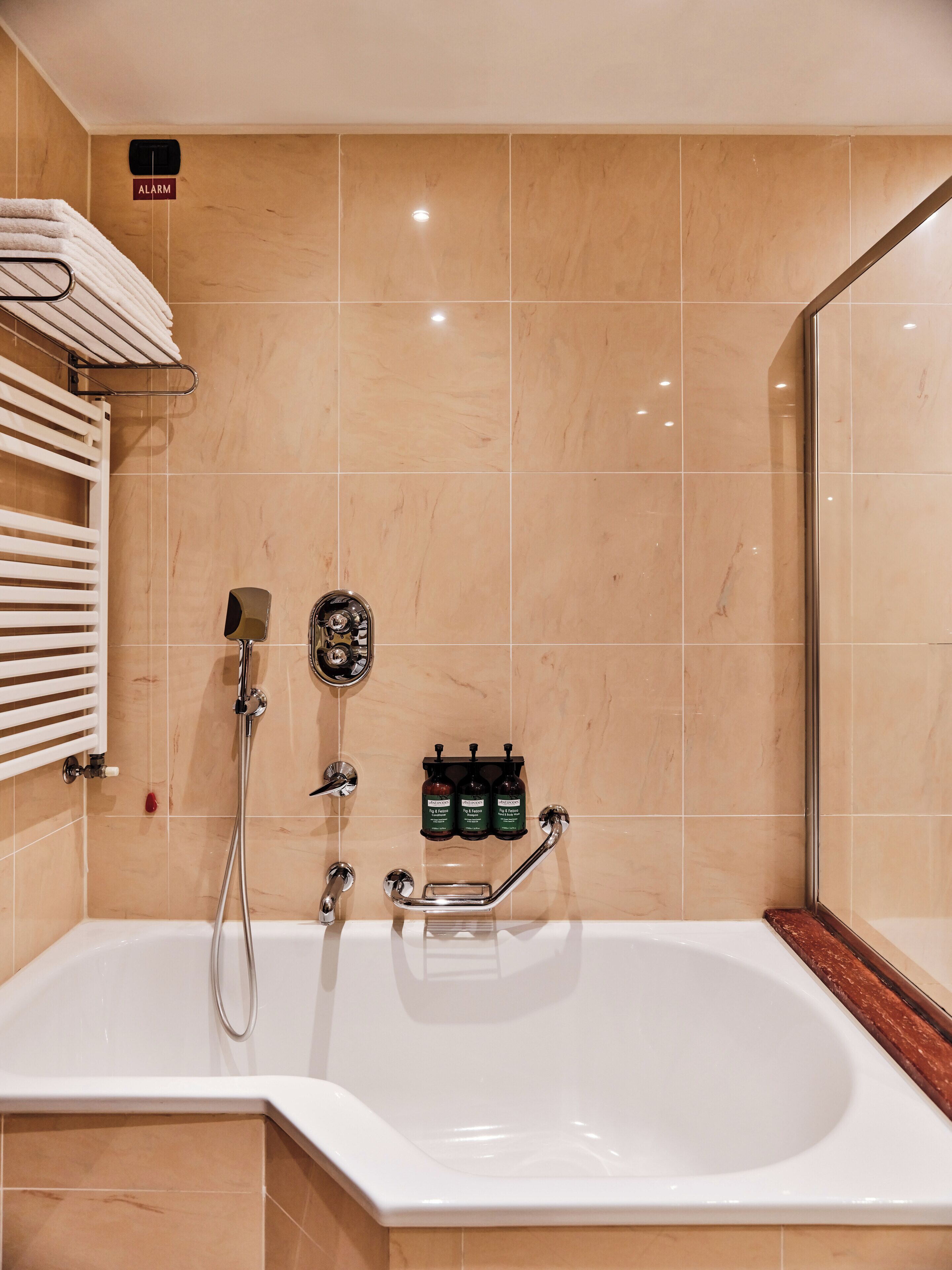 Une salle de bain moderne équipée d  ’une baignoire, d’un pommeau de douche à main et d’un distributeur de savon mural.
