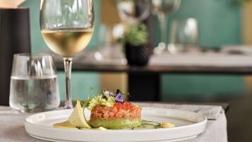 Un plato de comida con una copa de vino blanco sobre una mesa.