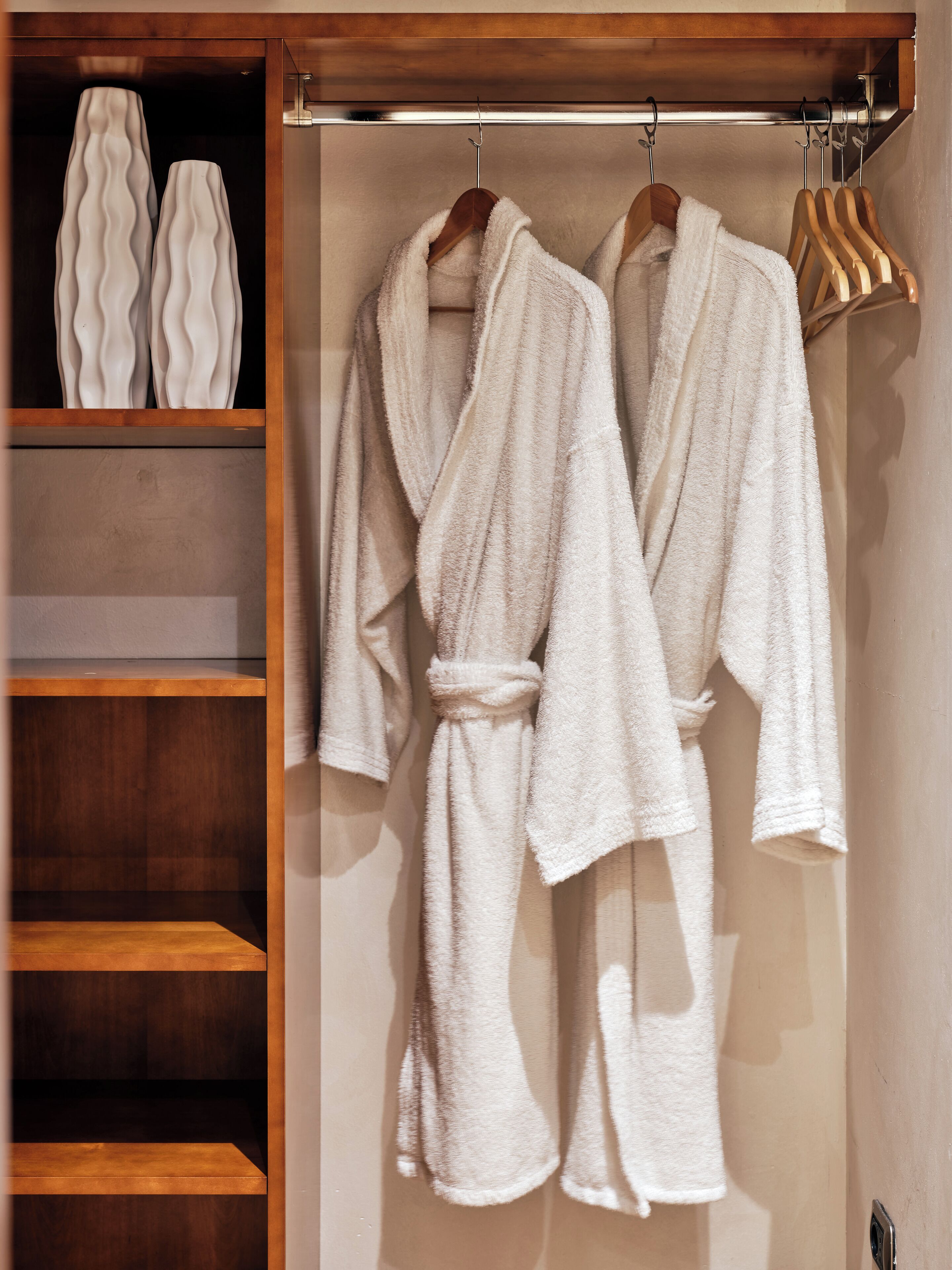 A walk-in closet with wooden shelves and a hanging robe rack.