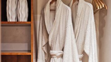 A walk-in closet with wooden shelves and a hanging robe rack.