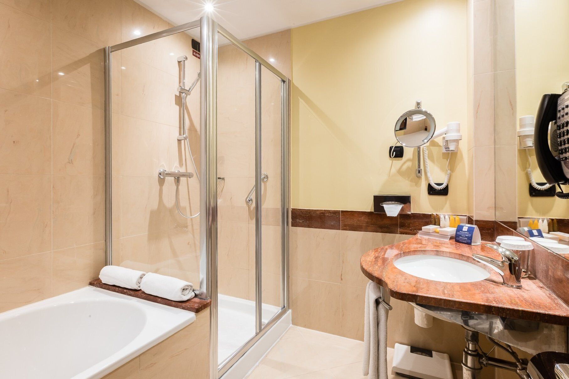 Un baño moderno con ducha envuelta en vidrio, una bañera independiente y un tocador con lavamanos y espejo.