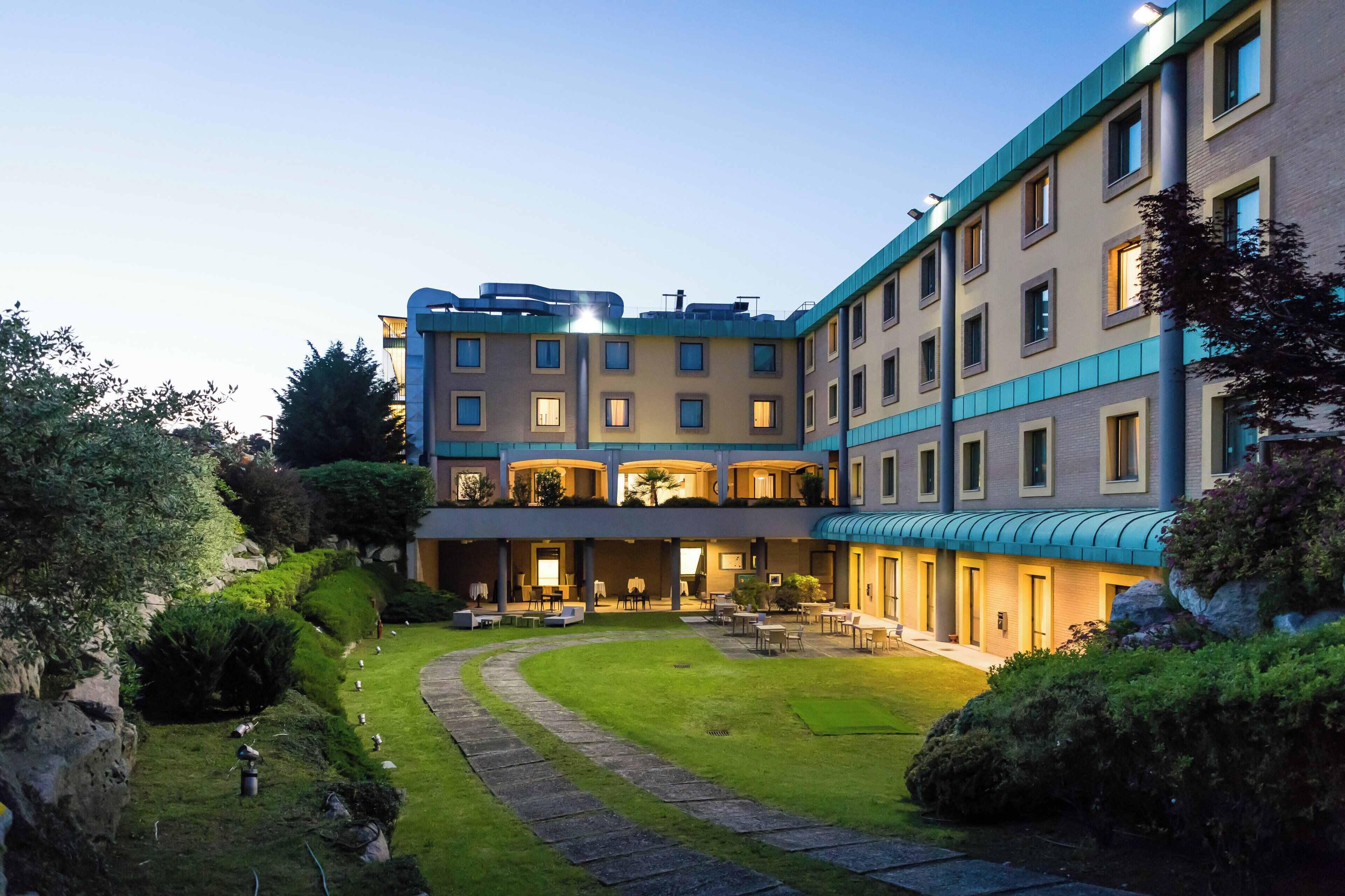 Een hotel met meerdere verdiepingen, een binnentuin, terras en een verzorgde tuin.