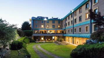 Un hotel a più piani con un cortile, posti a sedere all'aperto e un giardino curato.