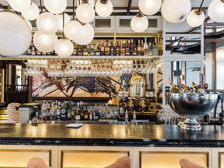 Un espace bar doté d’un comptoir élégant, de luminaires suspendus et d’une variété de bouteilles et de verres.