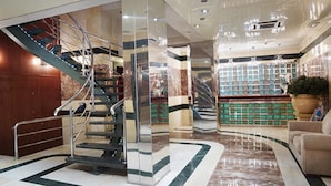 A modern lobby with a marble floor, a staircase, a reception desk, and a large potted plant. - MS Maestranza Málaga Centro (Málaga)