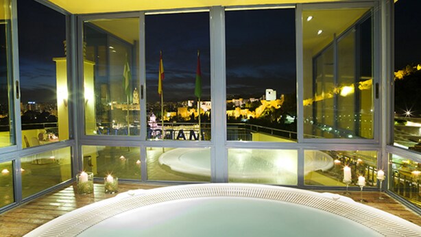 A modern hotel room with large windows offering a view of a cityscape at night. - MS Maestranza Málaga Centro (Málaga)