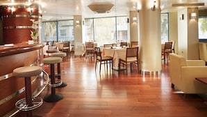 A restaurant interior with wooden flooring, bar stools, tables, and chairs. - MS Maestranza Málaga Centro (Málaga)