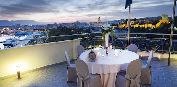A rooftop terrace with a round table set for dining, overlooking a cityscape with historic buildings and a river. - MS Maestranza Málaga Centro (Málaga)