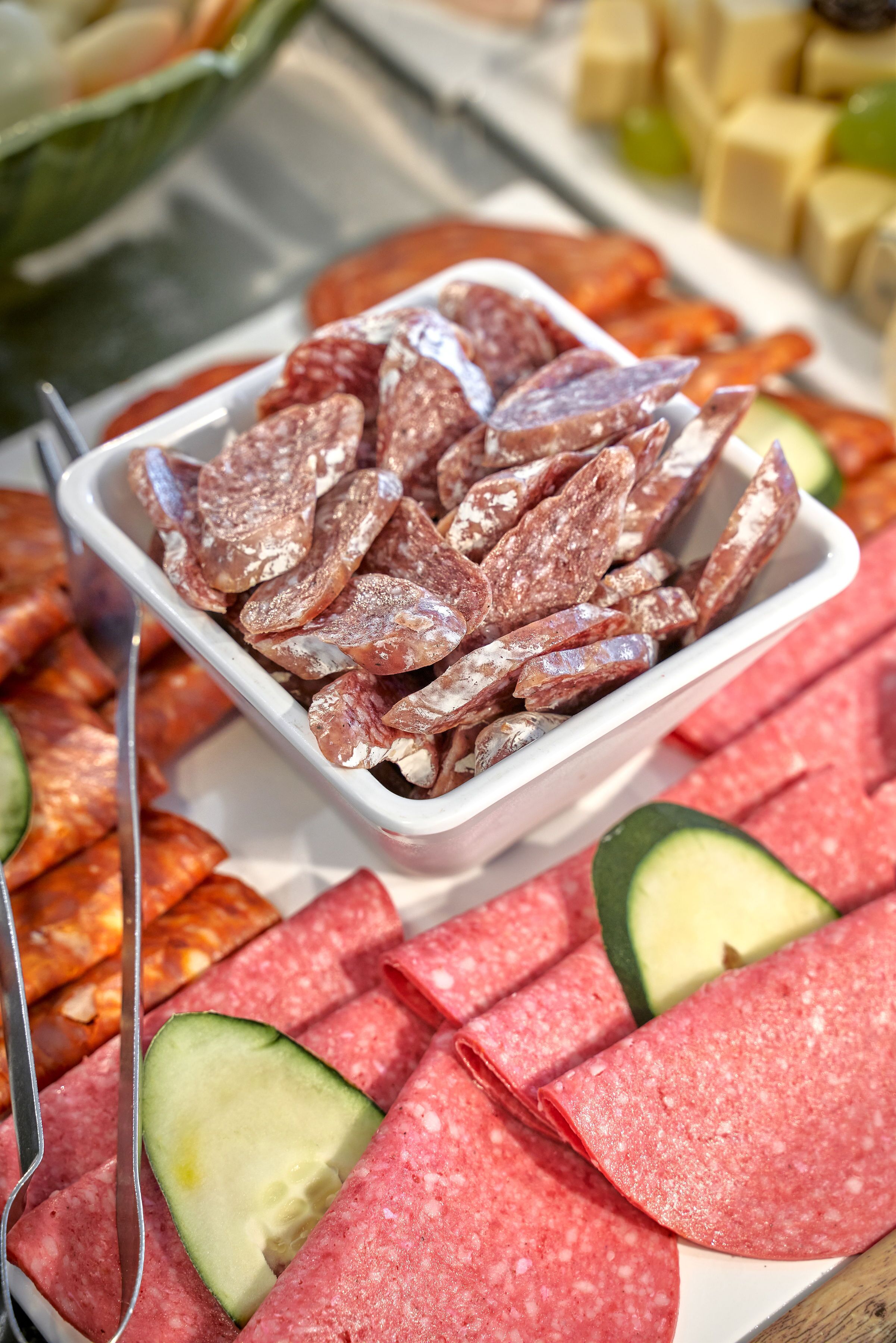 A variety of sliced meats and vegetables on a tray.