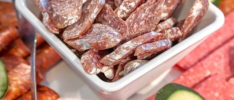 A variety of sliced meats and vegetables on a tray.