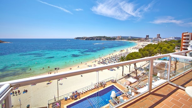 A balcony with a pool and a view of a beach and cityscape. - Flamboyan Caribe Hotel & Spa (Calvia)