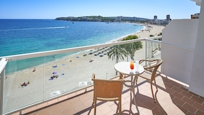 A balcony with a table and chairs overlooking a beach with umbrellas and people. - Flamboyan Caribe Hotel & Spa (Calvia)