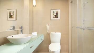 A bathroom with a white sink, a toilet, and a shower. There are framed pictures on the wall.