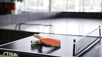 Una mesa de ping pong con una red, una paleta y una pelota.