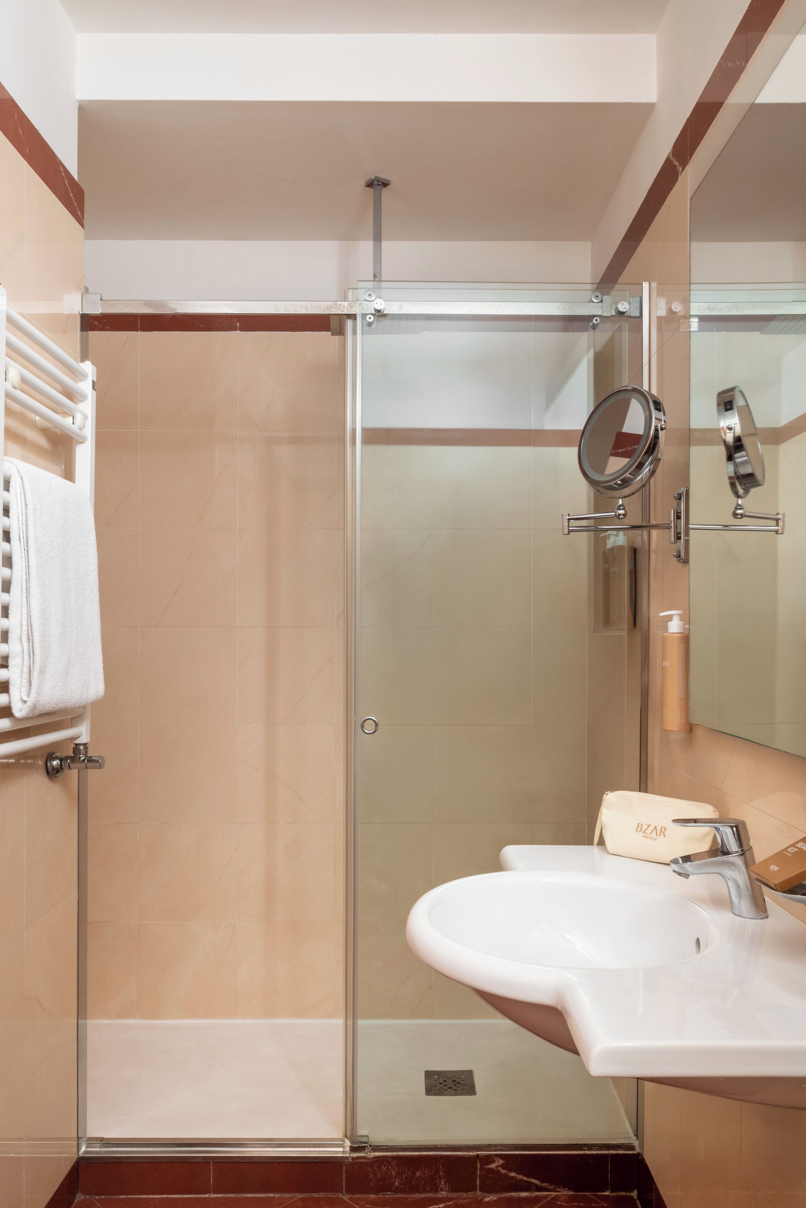 Un bagno moderno con doccia vetrata, lavabo bianco e porta asciugamani.