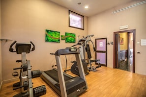 Un gimnasio con cintas de correr, máquinas de pesas y mancuernas.