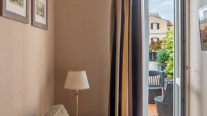 Ein Hotelzimmer mit Sofa, Lampe, einem Fenster mit Vorhängen und gerahmten Bildern an der Wand.
