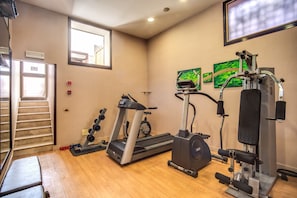 Un gimnasio con cinta de correr, elíptica y máquinas de pesas.