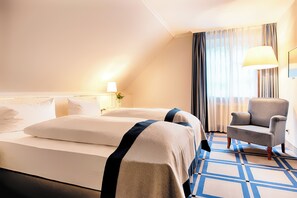 A hotel room with a large bed, a chair, a lamp, and a window with curtains. -  Hotel SchreiberHof (Aschheim)