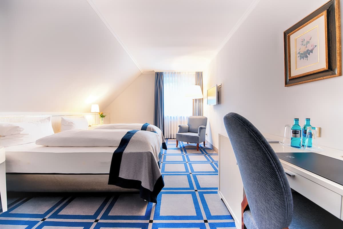 A hotel room with a bed, a desk, a chair, and a TV.