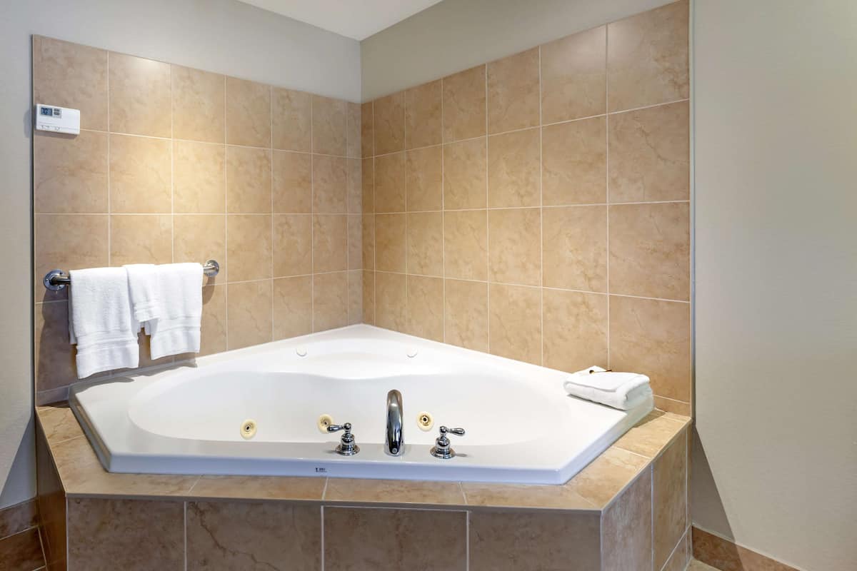 A modern bathroom with a large bathtub, a towel rack, and a control panel on the wall.