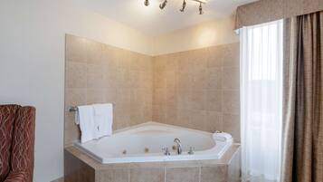 A modern bathroom with a large bathtub, a towel rack, and a shower curtain.