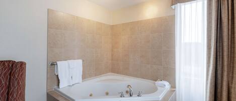 A modern bathroom with a large bathtub, a towel rack, and a shower curtain.