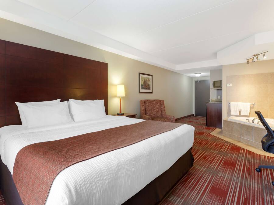 A hotel room with a large bed, a desk, a chair, a bathroom with a bathtub, and a shower.