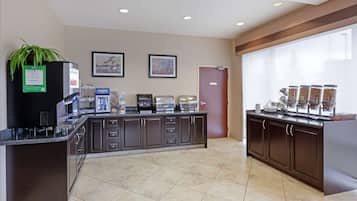 A modern kitchen with a coffee station, a refrigerator, and a large window.