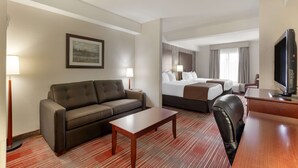 Ein Hotelzimmer mit Sofa, Bett, Schreibtisch, Fernseher und Lampe.