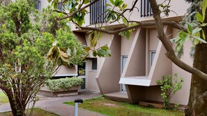 A modern building with a geometric facade, a small garden area with a tree, and a pathway leading to the entrance. - Albergo Leonardo (Brescia)