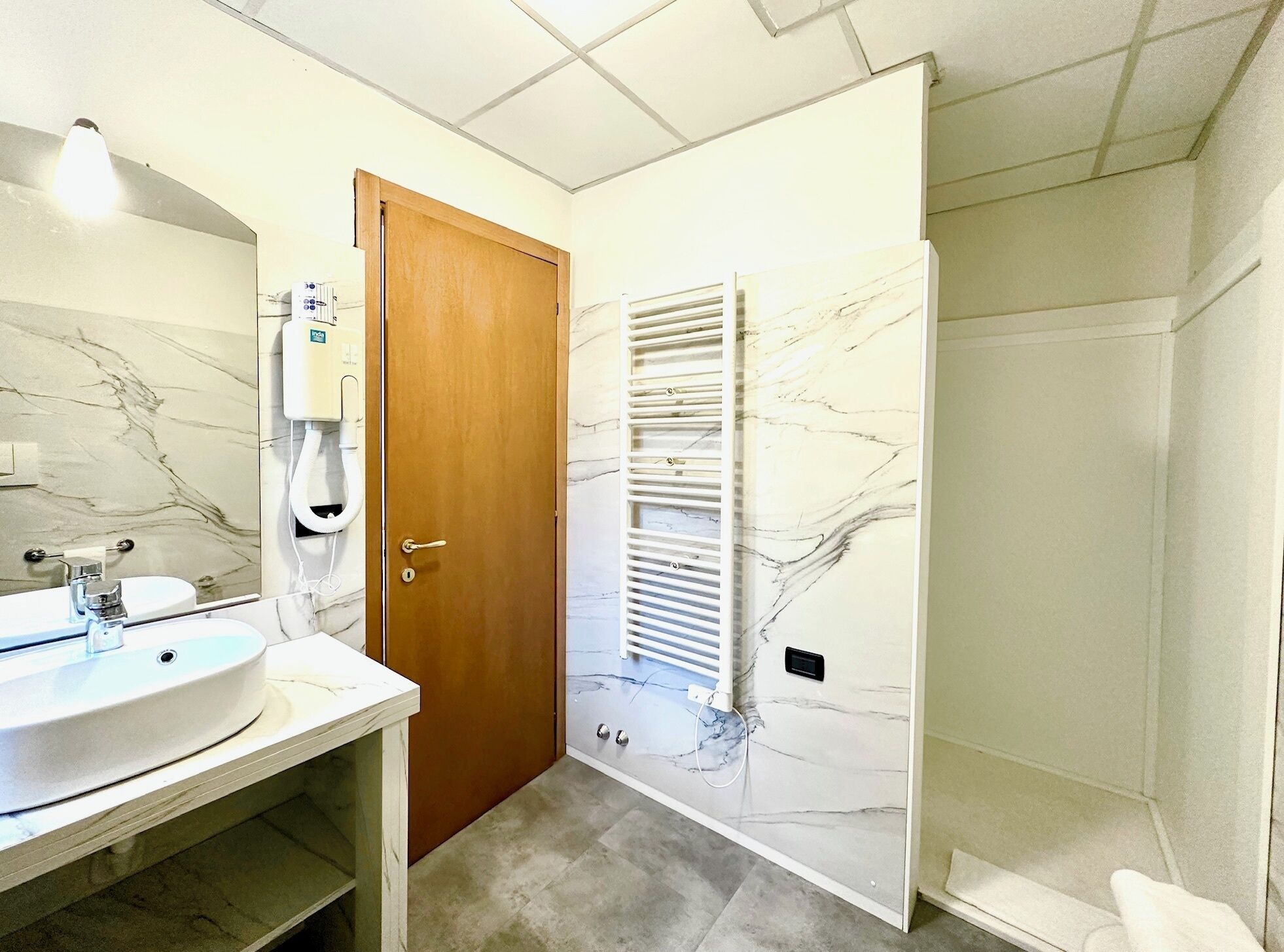 Un bany amb un lavabo de marbre, una porta de fusta i un suport per a tovalloles.