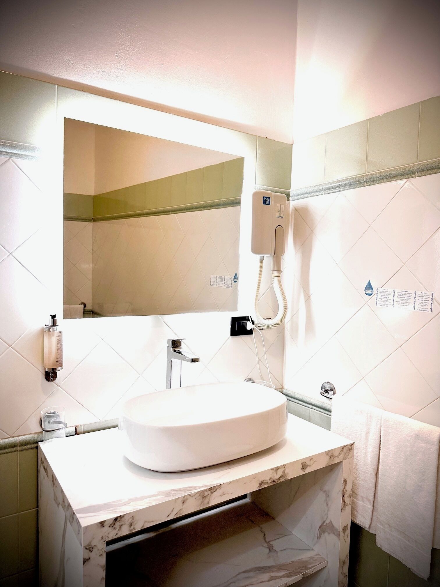 A bathroom with a white sink, a mirror, a towel rack, and a hand dryer.