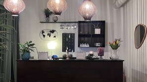 Un comptoir d’accueil en bois foncé, trois lampes suspendues, une carte du monde accrochée au mur, un calendrier et une petite plante.