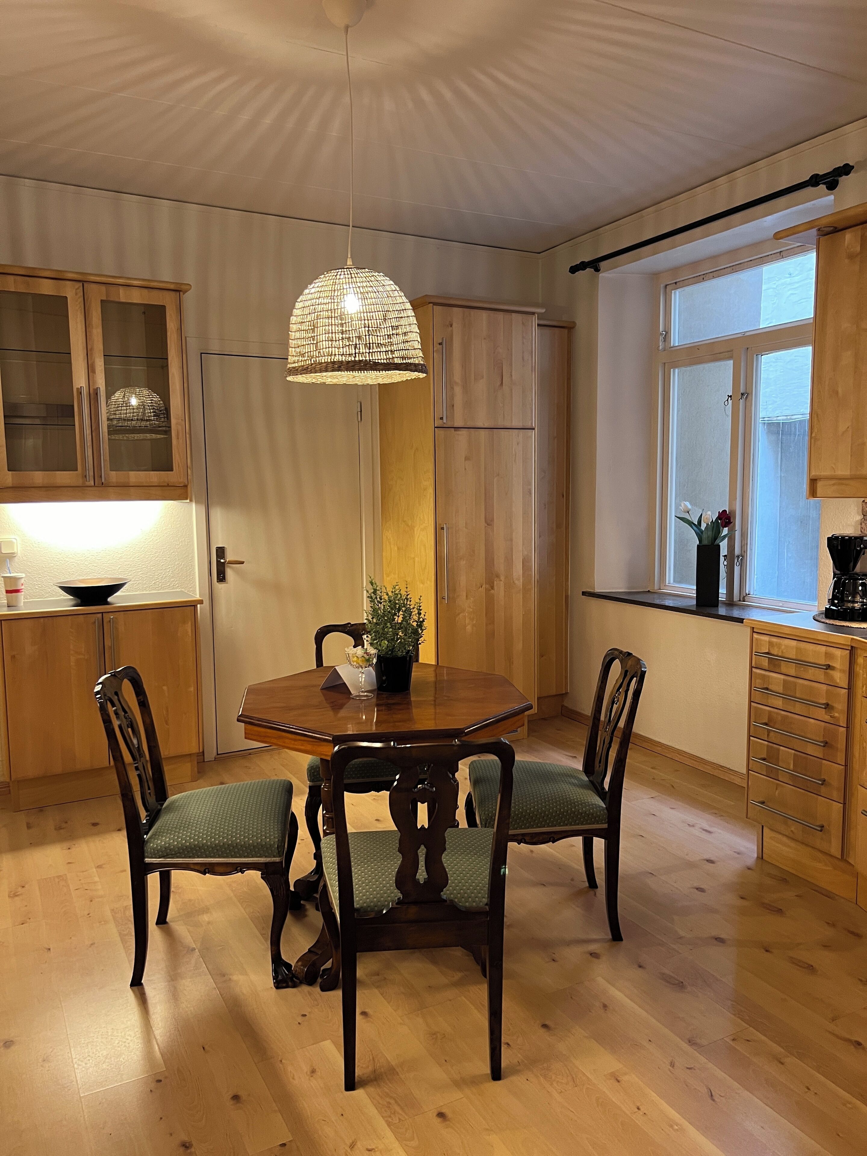 Un comedor con una mesa de madera, sillas y una lámpara colgante.