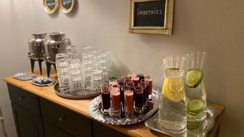 En bardisk med en tavla där det står "SMOOTHIES", ett bricka med små glas och en kanna med en citronskiva och gurka.