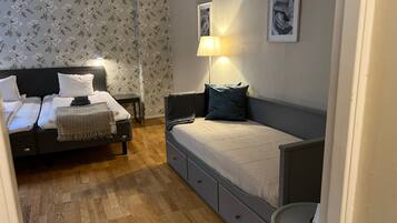 A bedroom with a bed, a sofa, a lamp, and a small table.