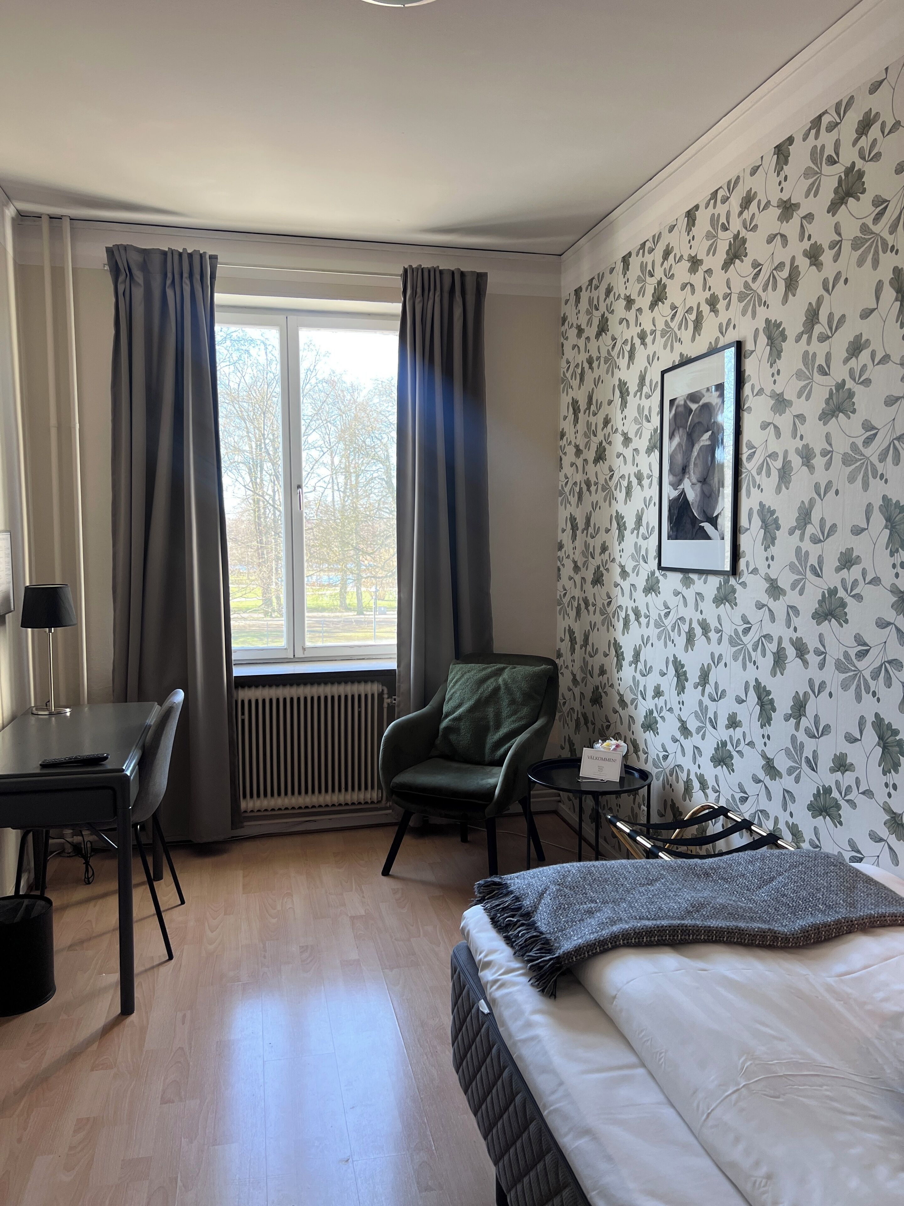 Ein Hotelzimmer mit Bett, Schreibtisch, Stuhl und Heizkörper.