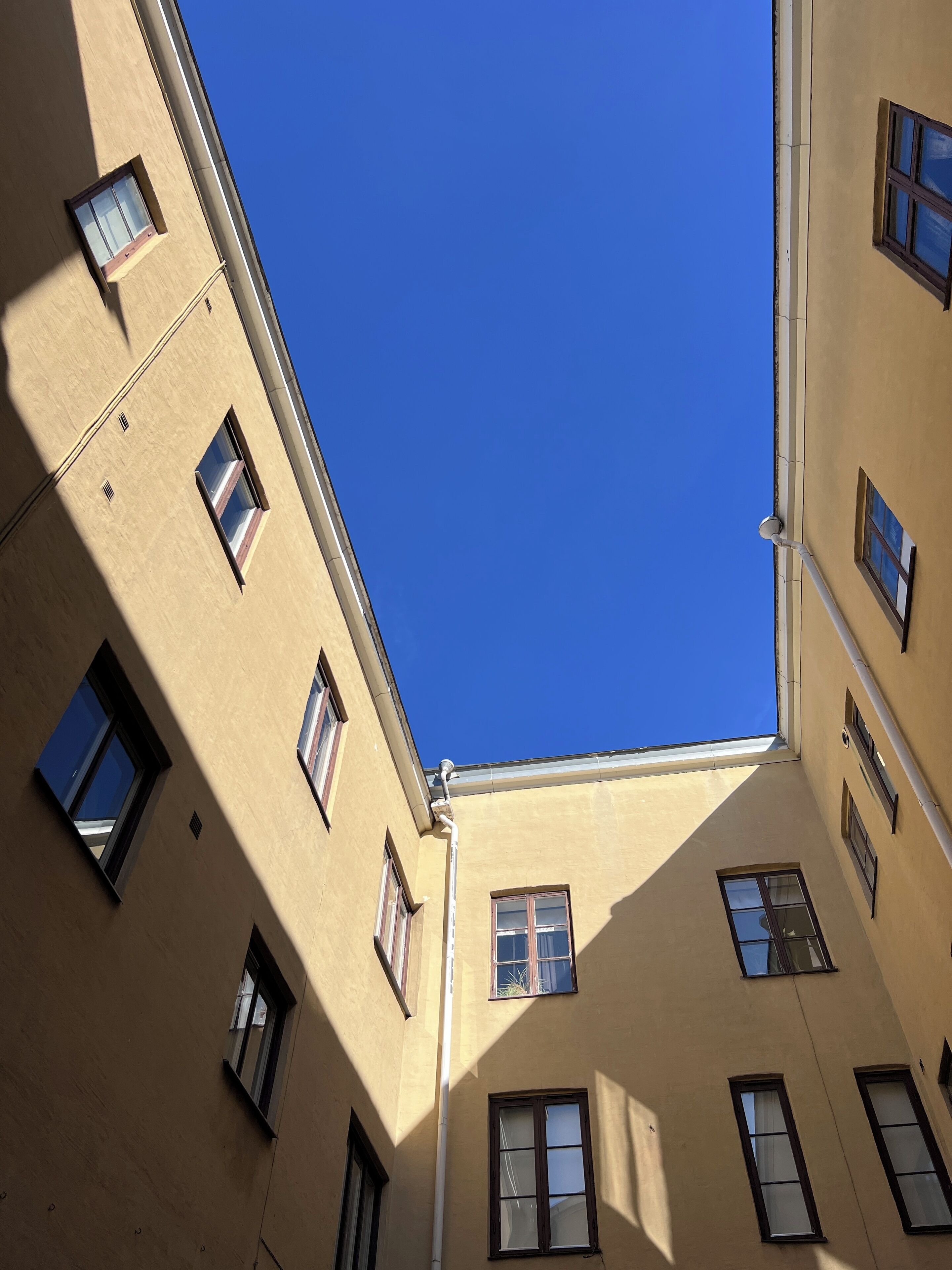 Een hoekzicht van een gebouw met veel ramen en een heldere blauwe lucht.