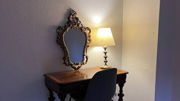 A corner desk with a chair, a lamp, and an ornate mirror on the wall.