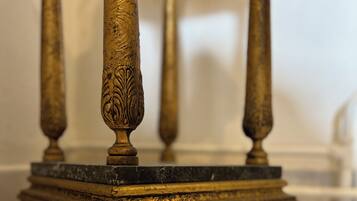A close-up of a golden, intricately designed table leg with a marble base.