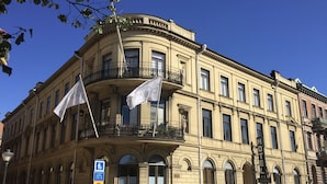 Un bâtiment historique doté d’un balcon d’angle, de nombreuses fenêtres et de drapeaux.